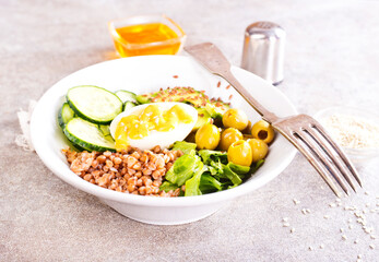 Bowl of tasty buckwheat porridge and egg on table