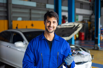 Portrait hispanic latin male mechanic repairs car in garage. Auto car mechanic professional working and checking car engine at garage. Car repair and maintenance