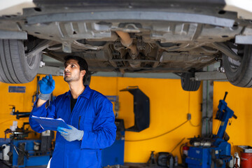 Portrait hispanic latin male mechanic repairs car in garage. Auto car mechanic professional working and checking car engine at garage. Car repair and maintenance