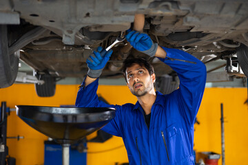 Under car. hispanic latin male mechanic repairs car in garage. Closeup hand. Auto car mechanic checking the oil level of the car engine. Car repair and maintenance