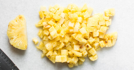 Top view of diced pineapples on a marble countertop, overhead view of chopped pineapples on a white...