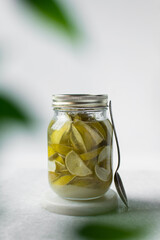 Lime cheong in a glass jar on a white background, korean lime cheong in a transparent jar, limes in sugar syrup