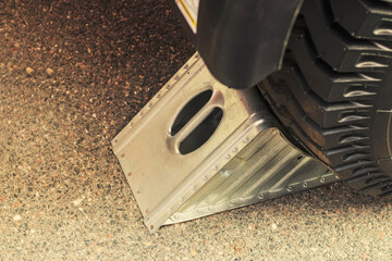 a metal stop on a large industrial machine. A wedge or block used to prevent a wheel from rolling. A device used to brake the wheels of heavy machinery close-up