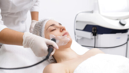 A cosmetologist performs RF lifting and ultrasound facial tightening in a modern salon. This advanced treatment rejuvenates and firms skin, perfect for showcasing effective beauty solutions.