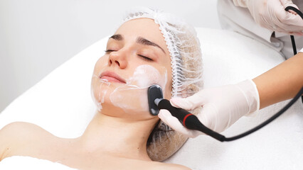 A cosmetologist applies radiofrequency lifting to a young woman in a modern clinic. This advanced...