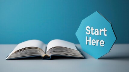 An open book beside a sign that reads 'Start Here', ideal for concepts of education, learning, and motivation.