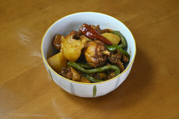 fresh braised chicken with potatoes and green beans and red peppers in the white bowl