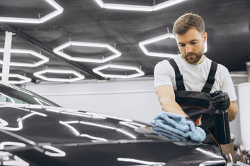 Car service man spraying water and washing on car body before applying anti-gravity film