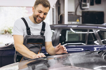 A car wrapping specialist applies a polyurethane film to the car. Selective focus. PPF protective film against chips and scratches. Car wrapping.