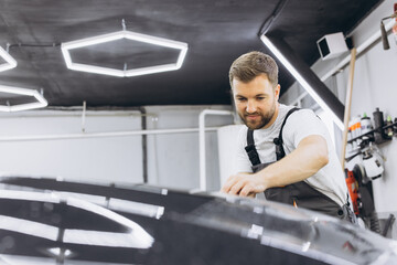 A car wrapping specialist applies a polyurethane film to the car. Selective focus. PPF protective...