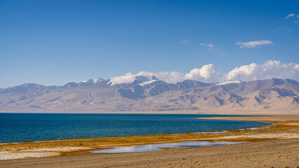 Colorful landscape view of high altitude Karakul lake shore and snow capped mountains in background, Murghab, Gorno-Badakhshan, Tajikistan Pamir