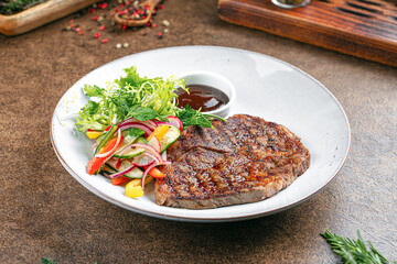 Portion of grilled beef steak with salad and sauce