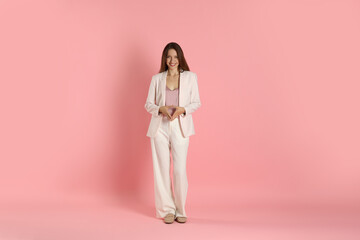 Beautiful woman in stylish white suit on pink background