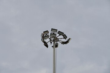 High mast lighting pole lights. Round sport light with white cloud sky background.