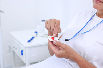 Senior woman with emergency call button on bed in hospital, closeup