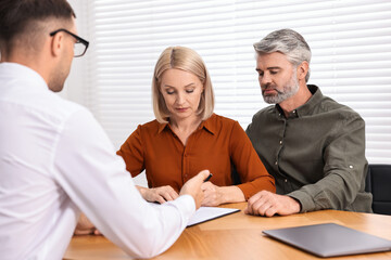 Obraz premium Pension plan. Couple consulting with insurance agent at table indoors