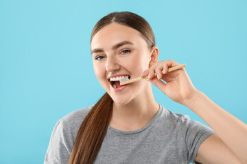 Beautiful woman brushing her teeth on light blue background