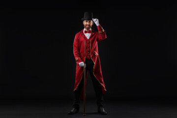 Portrait of showman in red costume and hat on black background