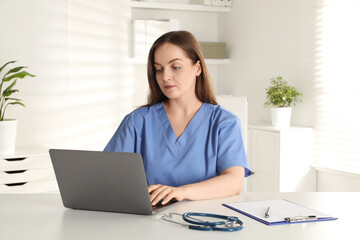 Young nurse working with laptop at desk in hospital