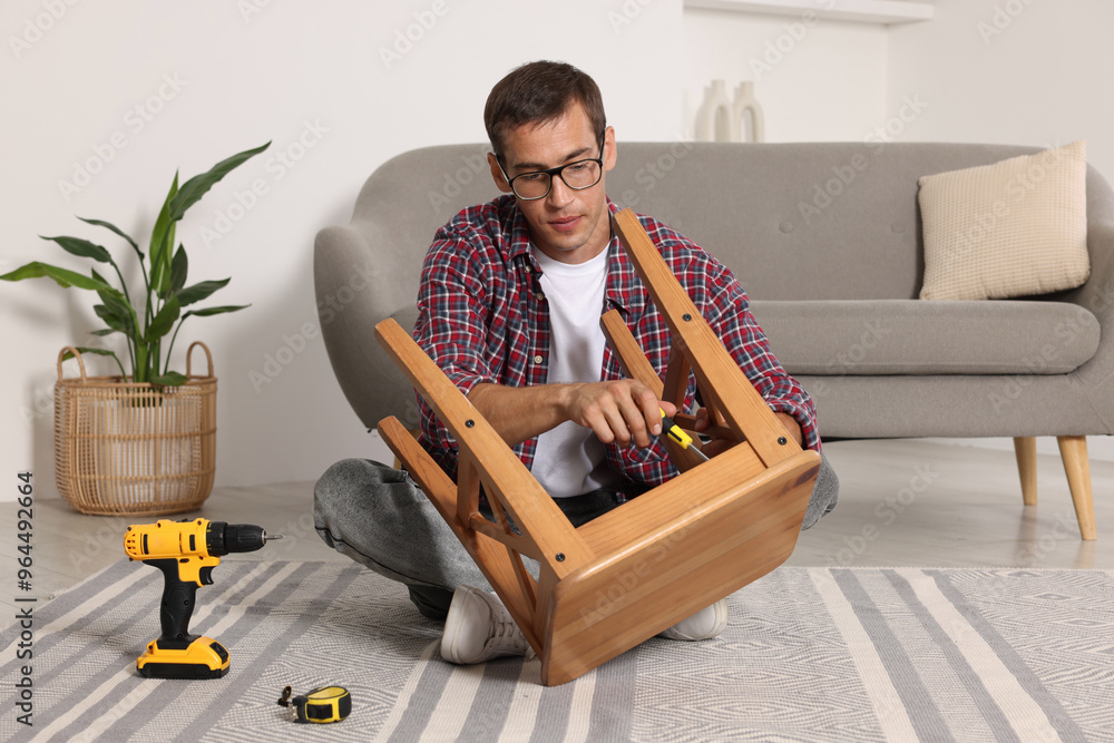 Canvas Prints Man repairing wooden stool with screwdriver indoors