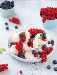 White sweet traditional merenques with berries on the plate