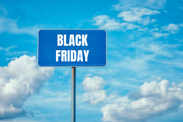 Black friday message written on blue metal sign with cloudy sky background. Conceptual black friday symbol. Copy space.