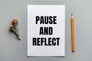 Pause and reflect message written on white paper with a pencil on gray background. Conceptual pause and reflect symbol. Copy space.