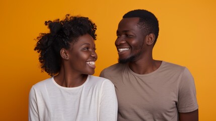 Obraz premium A couple shares a genuine moment of joy, smiling at each other against a bright orange background, reflecting their deep connection and happiness.