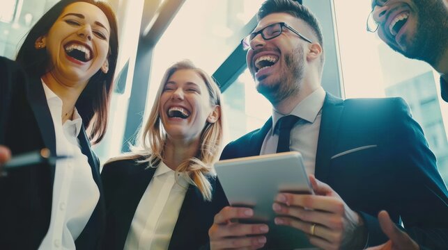 A group of colleagues share a hearty laugh in a bright office, capturing a moment of joy and camaraderie during a modern workday.