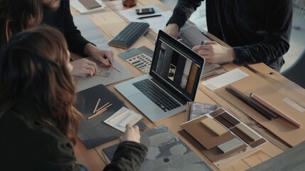 A design team collaborates over samples and a laptop on a cluttered wooden table, exuding creativity and teamwork.