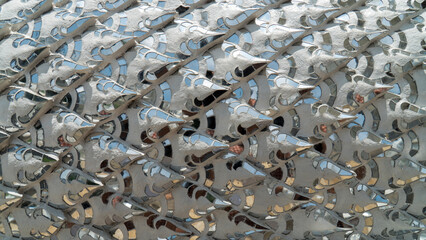 Close-up of shiny razor wire coils, showcasing intricate patterns and sharp edges, reflecting light in an industrial setting.