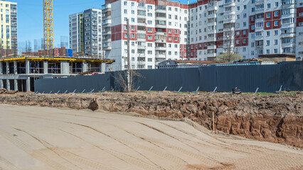 Sand leveling during the construction of roads and buildings. The construction site is fenced with a metal fence. Earthworks. A bulldozer leveled the sandy soil for paving the road surface.