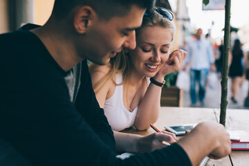 Happy male and female fellows preparing to college exams togetherness sitting at cafe terrace and...