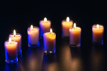 Burning candle on black background with backlight. Memorial Day.