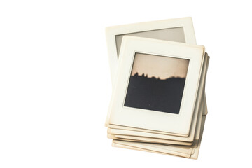 Stack of vintage photo slides with faded landscape image, isolated on blank background, ideal for nostalgic or retro themes.
