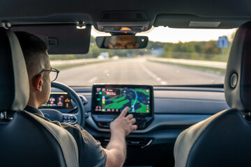 Man touching screen of a GPS navigation system in his car.