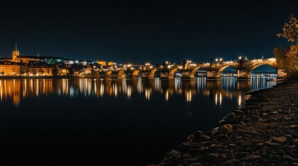 Obraz premium Night view of Prague's illuminated Charles Bridge with reflections on the Vltava River.