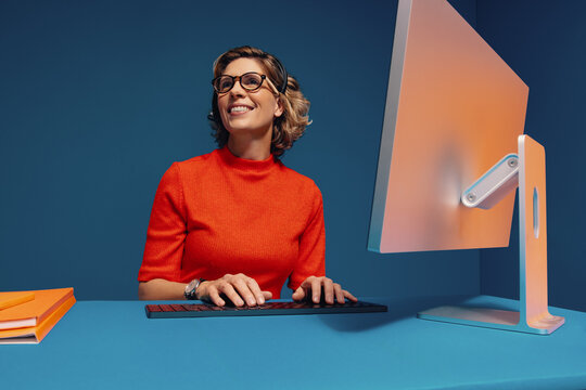 Mature colleague working on computer with vibrant color blocking clothes