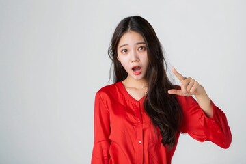 Fototapeta premium Shock Asian beautiful girl point beside her with red shirt in white background