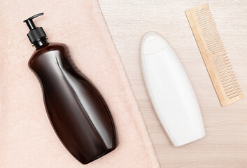 Black container with dispenser, white container for shampoo on wooden surface.