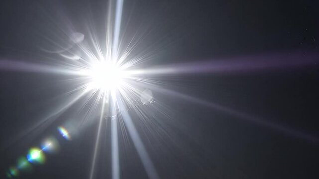 Bright lens flare with colorful light rays in slow motion for video background or special effects.