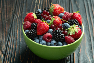 Mix of ripe colorful berries in bowl photography . Blueberry , strawberry , raspberry , blackberry and red currant . Top view