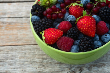 Mix of ripe colorful berries in bowl photography . Blueberry , strawberry , raspberry , blackberry and red currant . Top view