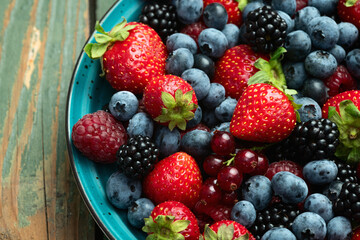 Mix of ripe colorful berries in bowl photography . Blueberry , strawberry , raspberry , blackberry and red currant . Top view