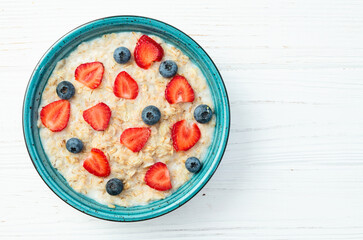 Homemade breakfast . Oatmeal with milk and berries . Top view