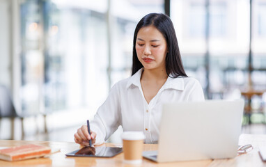 Obraz premium Asian Businesswoman Using laptop computer and working at office with calculator document on desk, doing planning analyzing the financial report, business plan investment, finance analysis concept. 