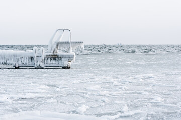 Diving board covered with ice and icicles in winter. Frozen sea on a very cold day.