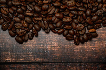 Coffee beans spilled on wooden table, dark stylish image