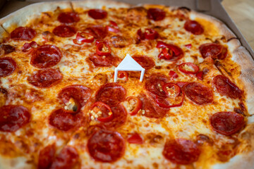 Close-up shot of a diavola pizza with a shallow depth of field. The pizza looks very tasty, featuring visible ham, chili peppers, and cheese.