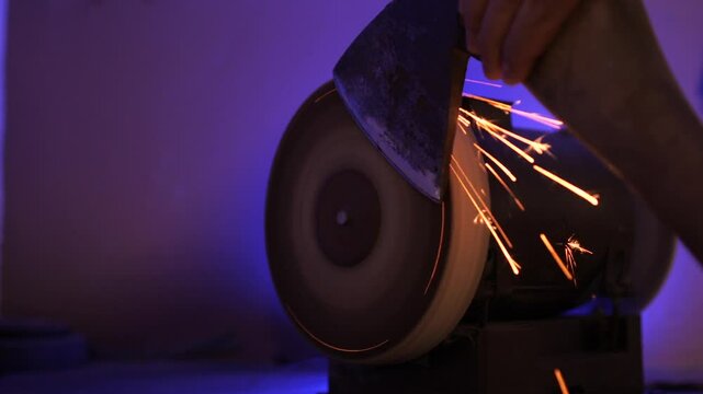 Blacksmith sharpening axe blade using grinding machine